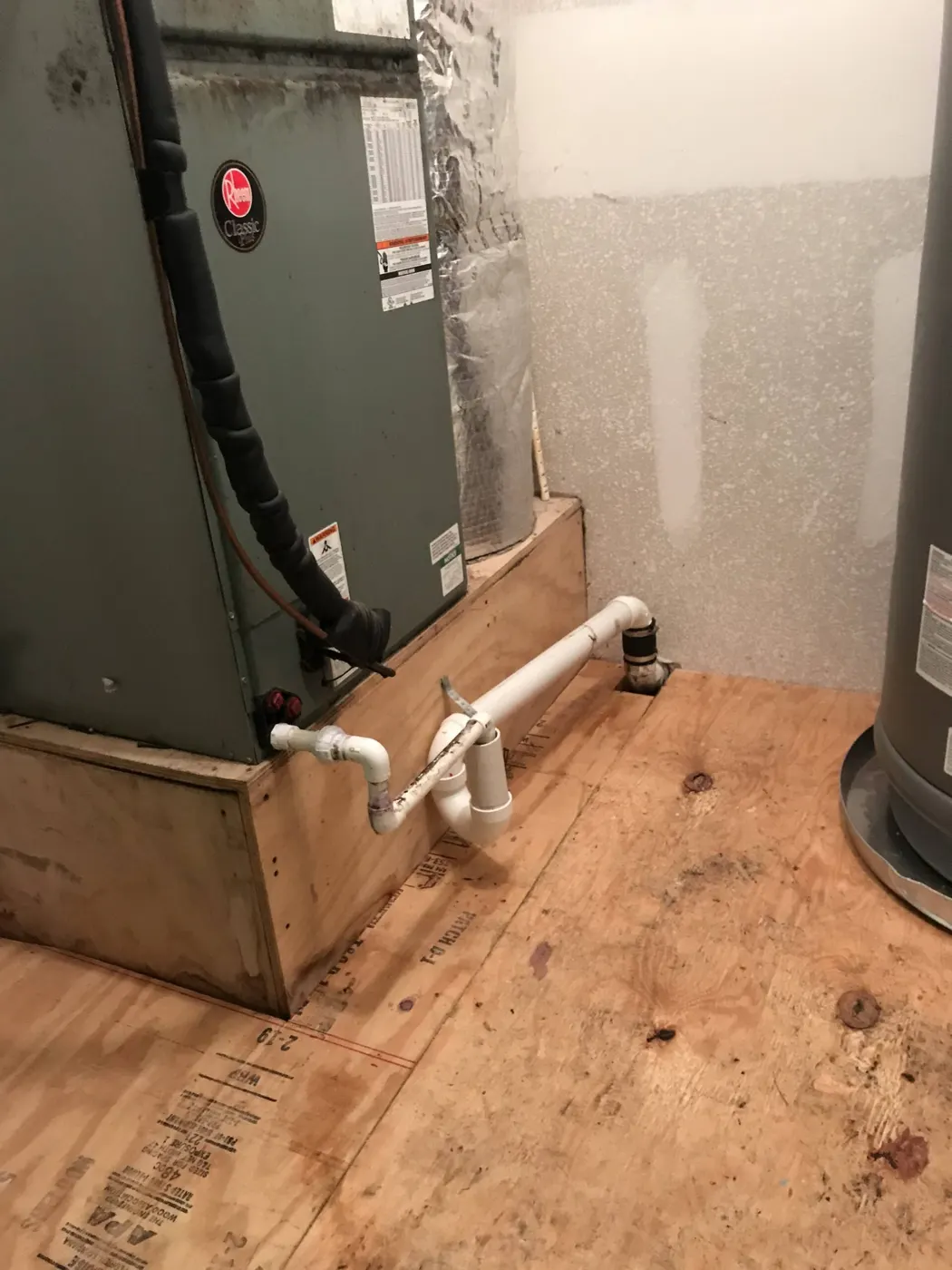 An indoor air handler on a platform with a new white PVC condensate drain line