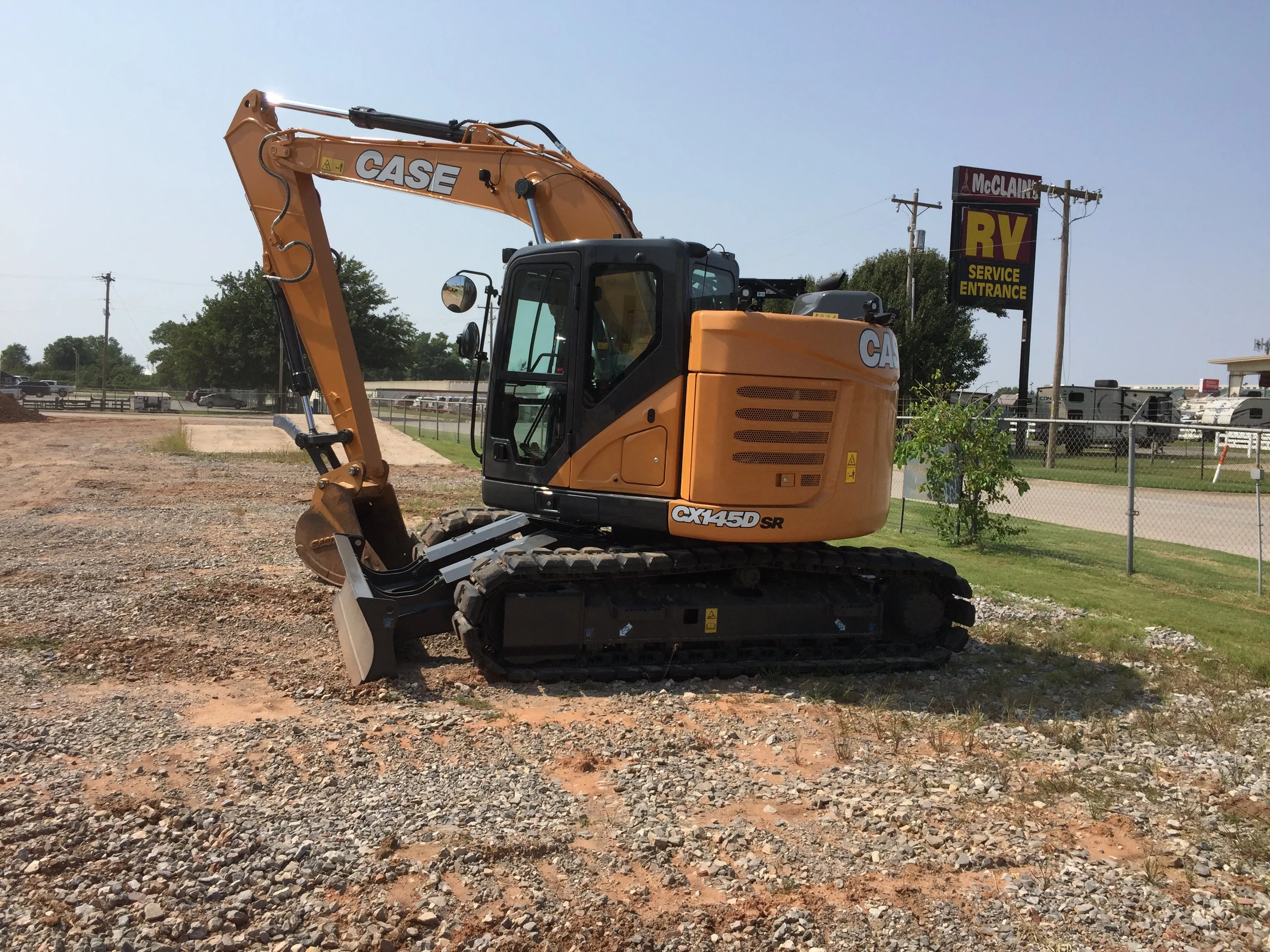 ABC's Case CX145 excavator parked on a gravel lot, bucket resting on the ground
