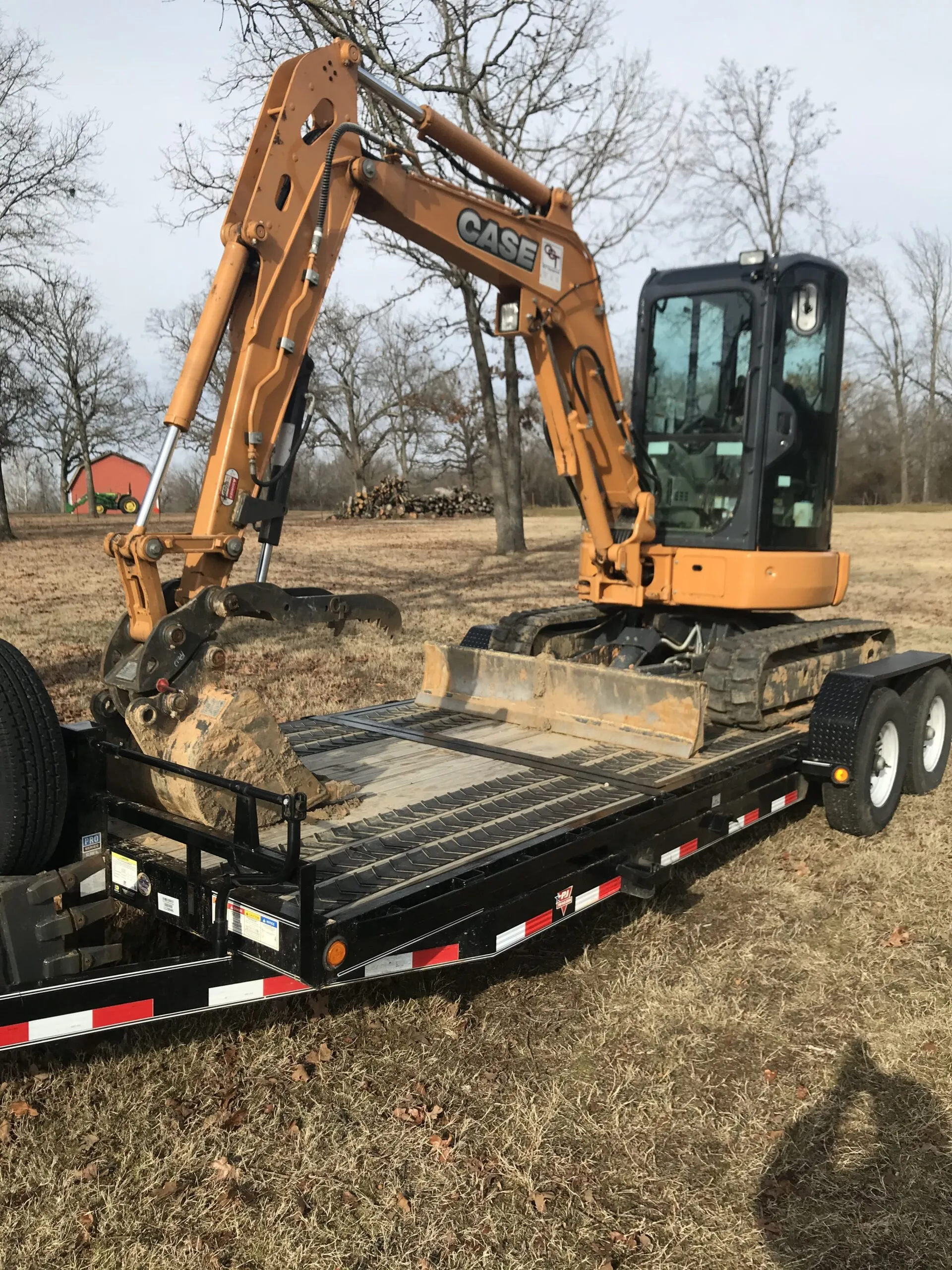 A Case excavator loaded on a trailer in a rural field