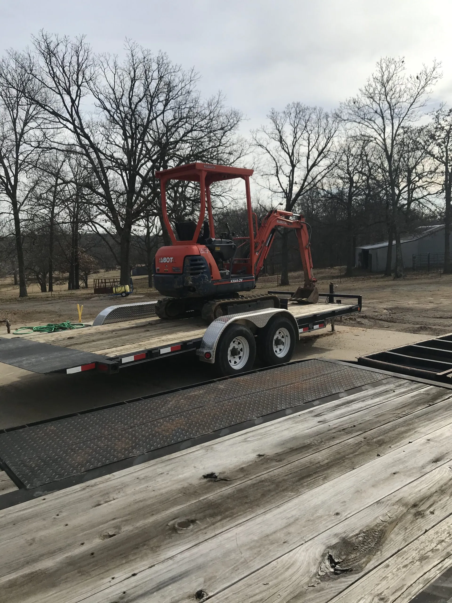 A Kubota mini excavator on a gooseneck trailer on a rural lot