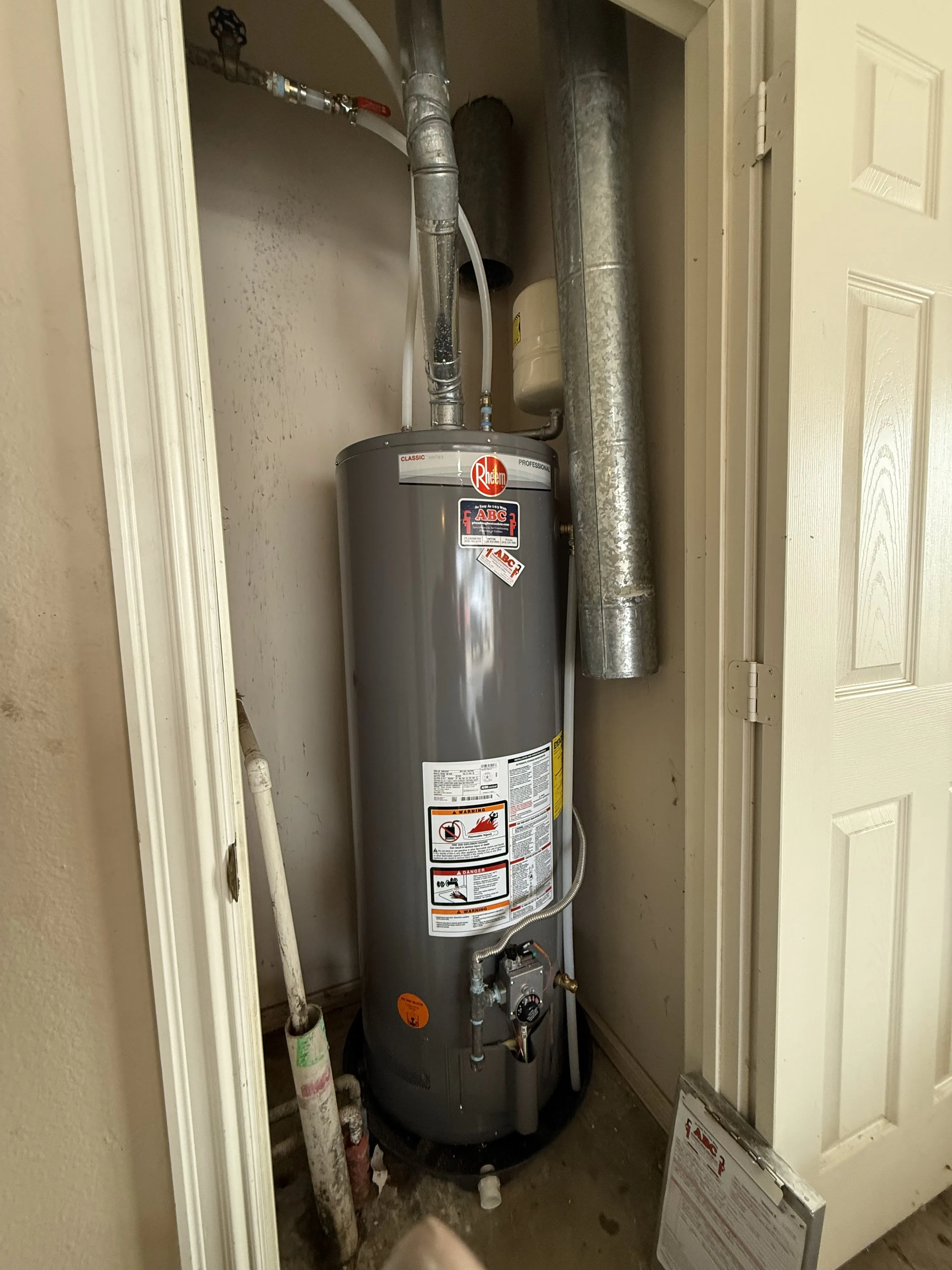 A new Rheem gas tank water heater installed in a utility closet