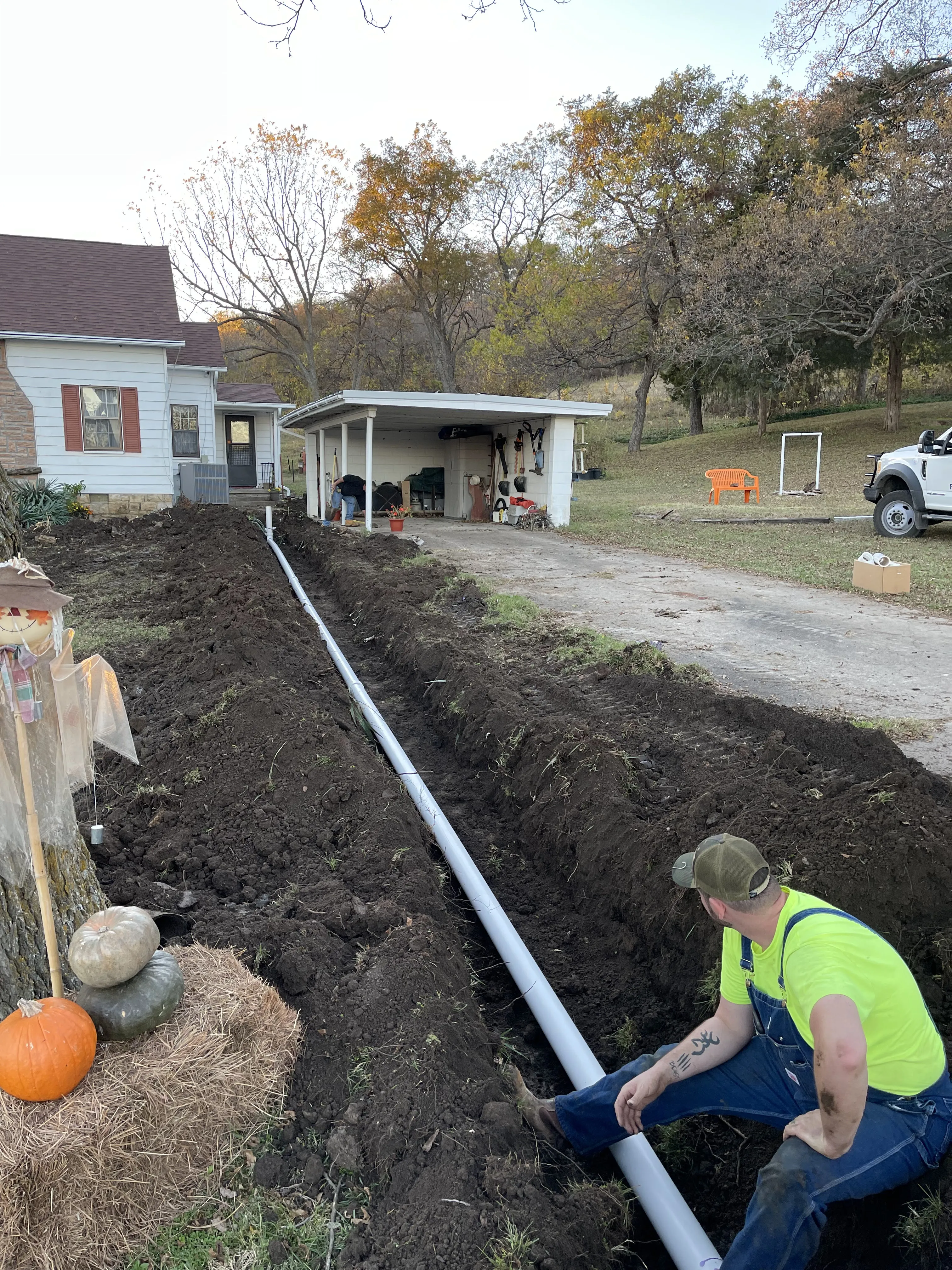 A crew member connecting a new sewer line in a trench running to a house